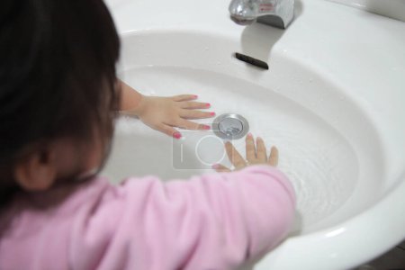 Foto de Niño asiático practicando buena higiene lavando las manos en el fregadero para prevenir - Imagen libre de derechos