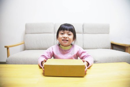 Photo for Authentic Asian Daughter's Happiness Smiling Portrait with a Parcel on Wooden Table - Royalty Free Image
