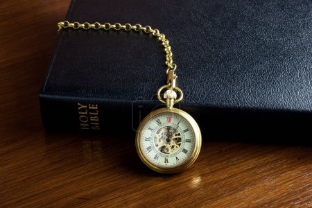 Photo for Vintage pocket watch and chain with a christian bible on a polished wooden surface - Royalty Free Image