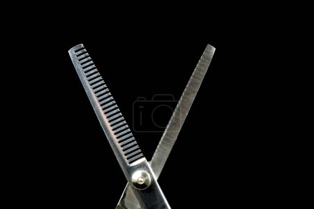Foto de Tijeras de peluquería para adelgazar el cabello aisladas sobre un fondo negro - Imagen libre de derechos