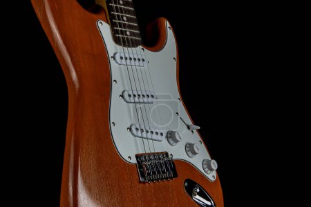 Photo for Solid wood electric guitar isolated upright on a black background - Royalty Free Image