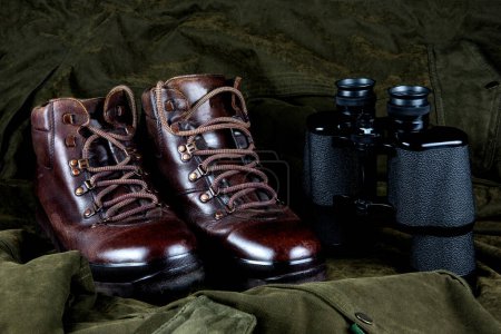 Binoculars and old hiking boots on an outdoor field coat