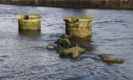 Old derelict stone bridge piers in an urban river estuary