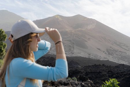 Photo for Woman with glasses places her cap in front of the Tajogaite volcano, she is out of focus and sideways, on La Palma island - Royalty Free Image