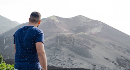 Photo for Man from behind and standing, looks at the crater of the Tajogaite volcano, from a viewpoint, on the Island of La Palma - Royalty Free Image