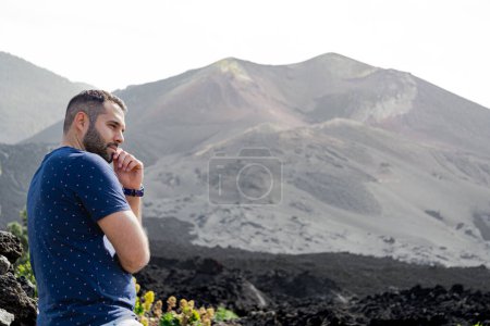Photo for Man standing thoughtfully looks at the flow of the Tajogaite volcano, at a viewpoint, on the island of La Palma - Royalty Free Image