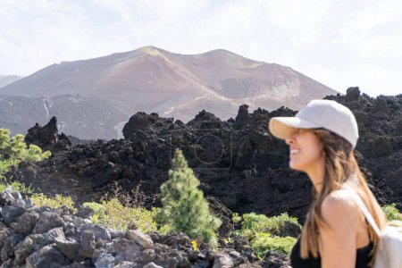 Photo for Close-up woman with cap walks smiling looking at the sky in front of the Tajogaite volcano viewpoint, on the island of La Palma - Royalty Free Image