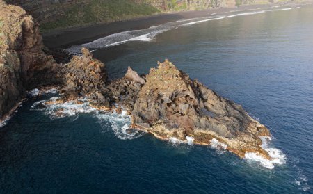 aerial drone view of the sea, a pointed cliff and Nogales beach in the background, in La Palma, Canary Islands