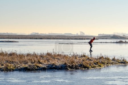 Téléchargez les photos : Den Helder, Pays-Bas. Décembre 2022. Patineur solitaire sur un étang gelé dans le paysage hivernal en Hollande. Photo de haute qualité - en image libre de droit