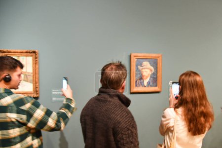 Foto de Amsterdam, Netherlands. January 2023. Visitors admiring and taking pictures of a self portrait of Vincent van Gogh. High quality photo - Imagen libre de derechos