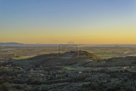 Aerial view at sunset of Val di Cornia with hills, cultivated fields and sea, Campiglia Marittima, Tuscany, Italy