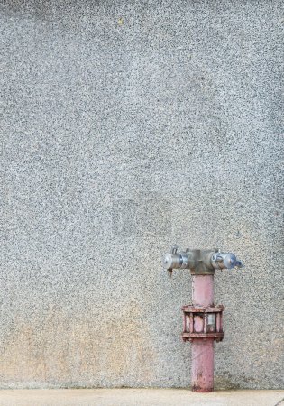 Téléchargez les photos : Point de tuyau d'incendie Installé sur un mur de plâtre pointillé L'apparence du tuyau a une couleur terne et ancienne. Indique une durée de vie relativement longue. légèrement rouillé - en image libre de droit