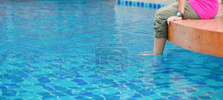 Photo for A woman putting her feet in the water in the swimming pool - Royalty Free Image