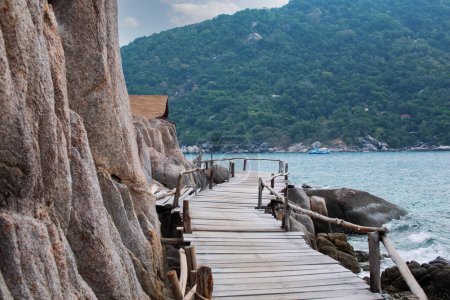 Photo for Brown wooden bridge along the hillside Rocks on the beach are rocks, rocky mountains and the sea near the island. concept of ecotourism - Royalty Free Image