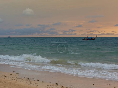 Photo for Waves lapping on the beach, sunset light, boats floating in the middle of the sea, romantic atmosphere. - Royalty Free Image