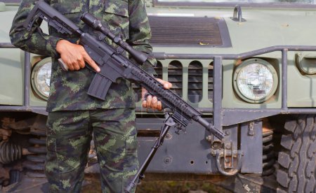 Photo for Soldier holding an assault rifle The background is a humvee. - Royalty Free Image