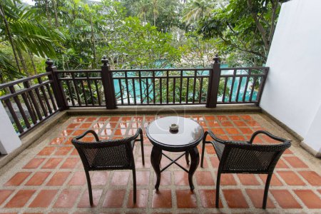 Photo for Chairs and tables on the balcony of the room near the tree-covered pool are perfect for relaxing. - Royalty Free Image