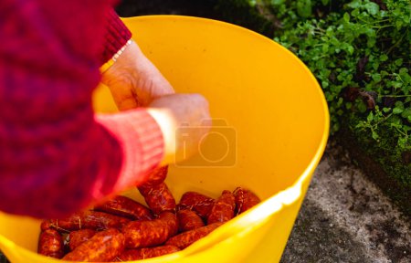 Foto de Manos manejando salchichas recién hechas en una bañera de plástico - Imagen libre de derechos
