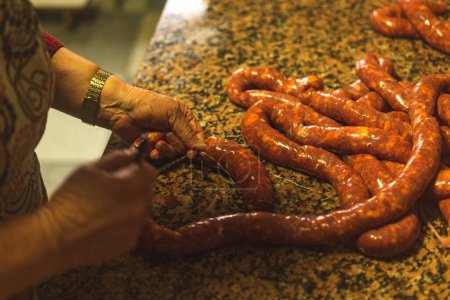 Photo for Two people knotting sausages whose sample is seen in the foreground - Royalty Free Image