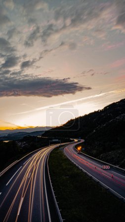 Foto de Autopista al atardecer donde se pueden ver las siluetas de las luces del coche en ambas direcciones - Imagen libre de derechos