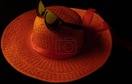 Foto de Sombrero de mujer naranja con gafas de sol negras colocadas en la parte donde va la cabeza - Imagen libre de derechos
