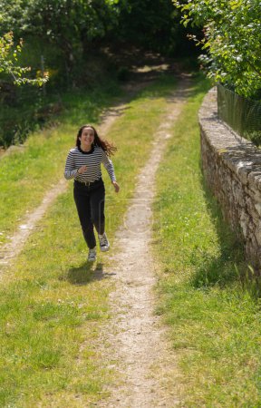Photo for Teenage girl runs with open arms along a path in the countryside - Royalty Free Image