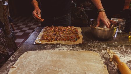 Foto de Manipular la masa para hacer una empanada con todos en una mesa de cocina - Imagen libre de derechos