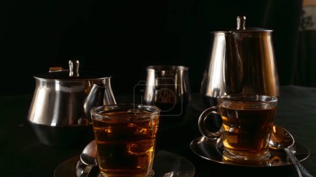 Zwei mit Tee gefüllte Glasbecher auf versilberten Metallplatten mit Behältern zur Lagerung der Flüssigkeit