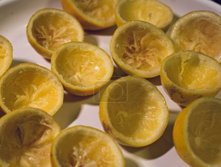 Frisch gepresste Zitronen in der Hälfte und Fruchtfleisch in einer elektrischen Entsaftungsmaschine entfernt