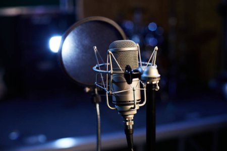 Microphone with pop shield closeup on the background of professional recording studio. Microphone stand with condenser for records vocals, speakers and sound of musical instrument. High quality photo