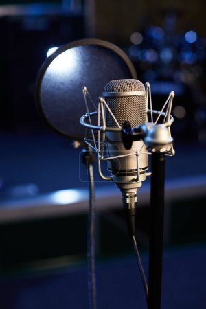 Micrófono con el primer plano del escudo pop en el fondo del estudio de grabación profesional. Soporte de micrófono con condensador para grabaciones vocales, altavoces y sonido de instrumento musical. Foto de alta calidad