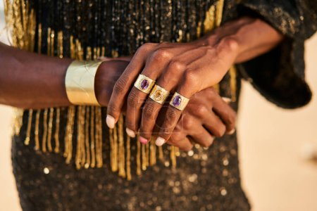 Photo for Transgender hands with brass jewelry rings, bracelets. Bipoc gender fluid biracial gay model poses with a manicure and golden jewellery in closeup. Androgynous drag person touches hands tenderly. - Royalty Free Image