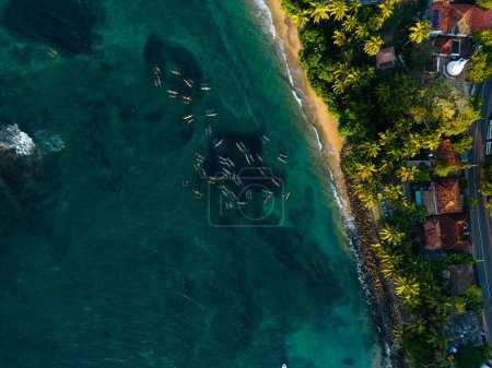 Téléchargez les photos : Drone shot capturant vue de dessus de la flotte de pêche dynamique au large, mer tranquille avec de petits bateaux, lumière aube éclairant paysage aquatique pittoresque, moyens de subsistance côtiers. Canots déclenchés aériens. - en image libre de droit