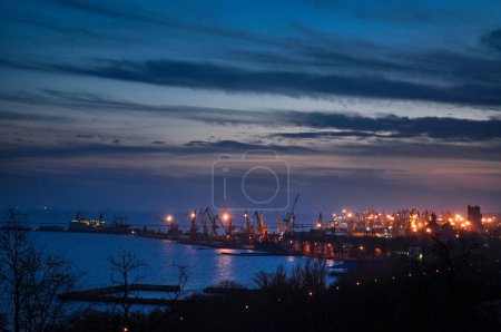 Photo for Dusk silhouette skyline, shipping logistics. Twilight over industrial harbor with cargo cranes, lit buildings, operational port area. Import export business trade, global economy transport background. - Royalty Free Image