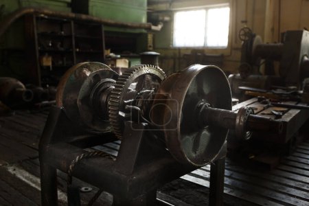 Antique mechanical gear assembly, engineering heritage in rustic plant. Retro industry tech, metal cogwheel device.