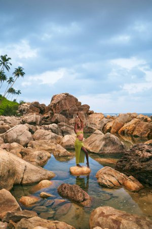 Androgyne schwarze lgbtq Mode-Modell posiert auf einem Stein in malerischen natürlichen Pool. Nichtbinäre biethnic Person in steht in stillem Wasser zwischen Felsen auf einer exotischen Insel. Gender queer. Stolzer Monat.