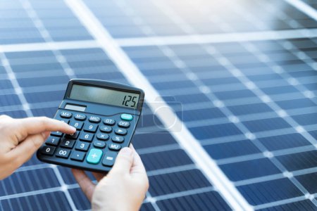 Photo for Someone is calculating the savings of use a solar panel system with a calculator - Royalty Free Image