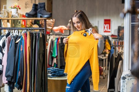 Photo for Portrait of an overweight woman trying on some clothes in a clothing store in the plus size section - Royalty Free Image