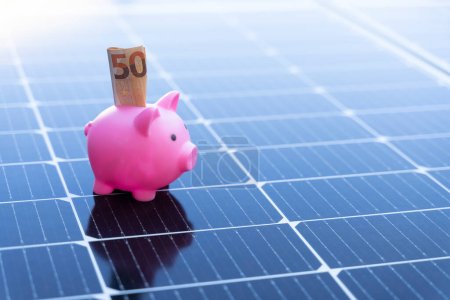 Téléchargez les photos : Image with copy space of energy saving concept with solar panels and a piggy bank with fifty euro banknote - en image libre de droit