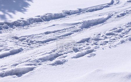 Téléchargez les photos : Dérive de neige sur la route, fond neigeux, texture de la neige avec traces de pneus de voiture, climat gelé, ombres sur la neige, gros plan, horizontal - en image libre de droit