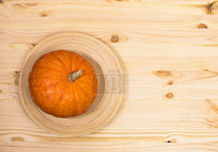 Téléchargez les photos : Citrouille jaune-orange sur un plat en bois sur une surface en bois clair, vue de dessus, copyspace sur la droite - en image libre de droit