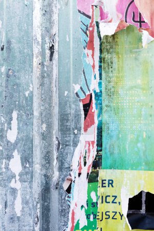 Una amplia gama de carteles de papel vibrantes, desgarrados y erosionados, adorna una pared metálica, formando una cautivadora exhibición abstracta con una mezcla de tonos vivos y texturas que emanan una estética urbana única.