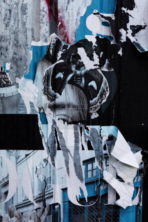 Foto de A torn blue and white paper collage with a butterfly wings in the center. The butterfly wings are black with white spots. The paper is torn in strips and reveals a building in the background. - Imagen libre de derechos
