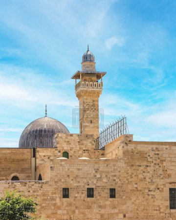 Téléchargez les photos : L'ancienne mosquée a des détails complexes et est entourée de grands murs de pierre. Le ciel est clair et clair avec quelques nuages tordus. Une excellente image pour les concepts de voyage, d'histoire ou de religion. - en image libre de droit