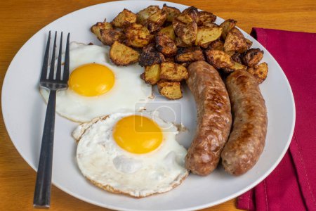 two fried eggs served with home fries  and italian sausages