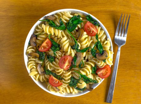 rotini pasta salad consisting of sauteed mushrooms and spinach with tomatoes, 