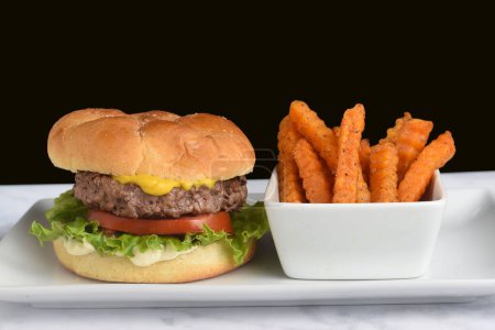 Photo for Hamburger  on a bulkie roll  served with  sweet potato fries - Royalty Free Image