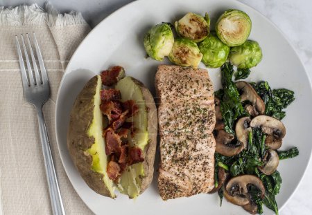 Photo for Season salmon with sauteed mushrooms and  spinach  served with baked potato with bacon, - Royalty Free Image