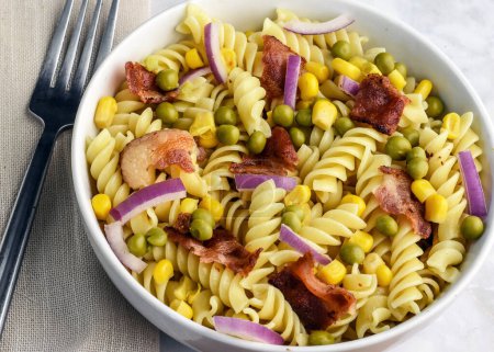 Téléchargez les photos : Salade de pâtes rotini servie avec maïs pois et bacon, - en image libre de droit