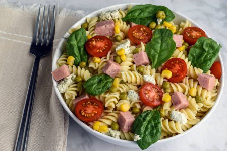 Téléchargez les photos : Salade de pâtes rotini composée de spam servi avec des tomates et des épinards - en image libre de droit
